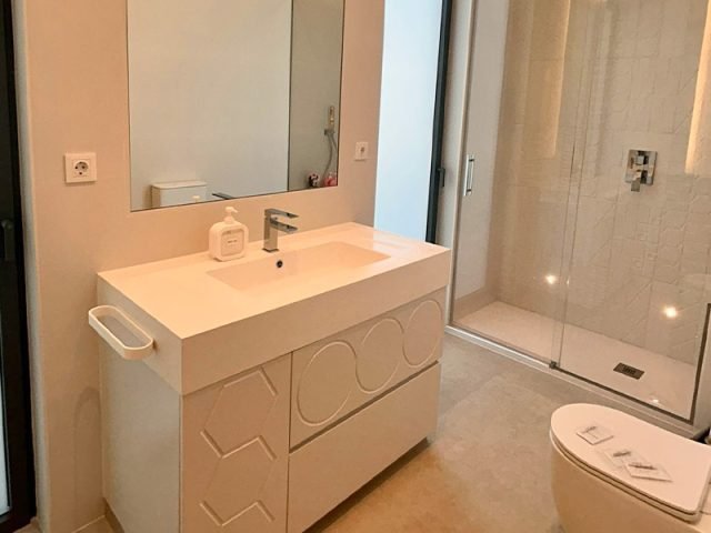 Mueble de bano con lavabo de Corian de Solid Creaciones instalado junto a ducha, foto real de clienta